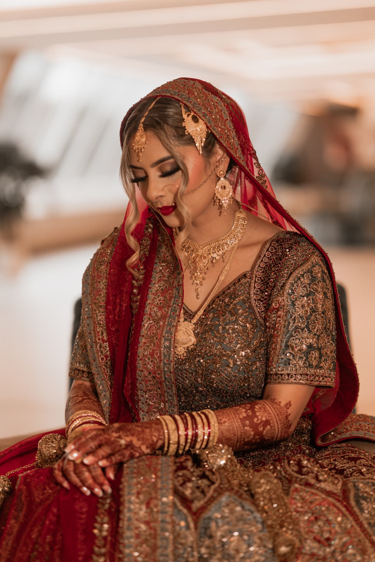 Bride seated in her richly embroidered red and gold wedding dress