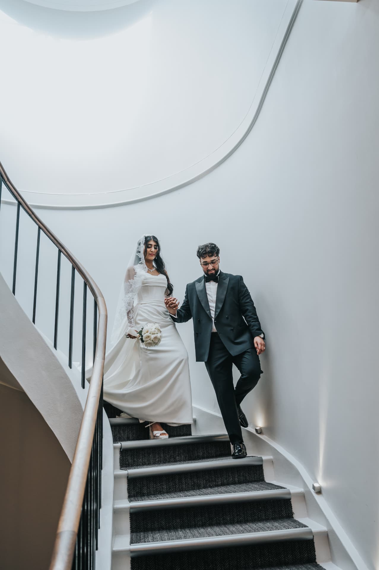 Bride and groom walking together down a sweeping staircase