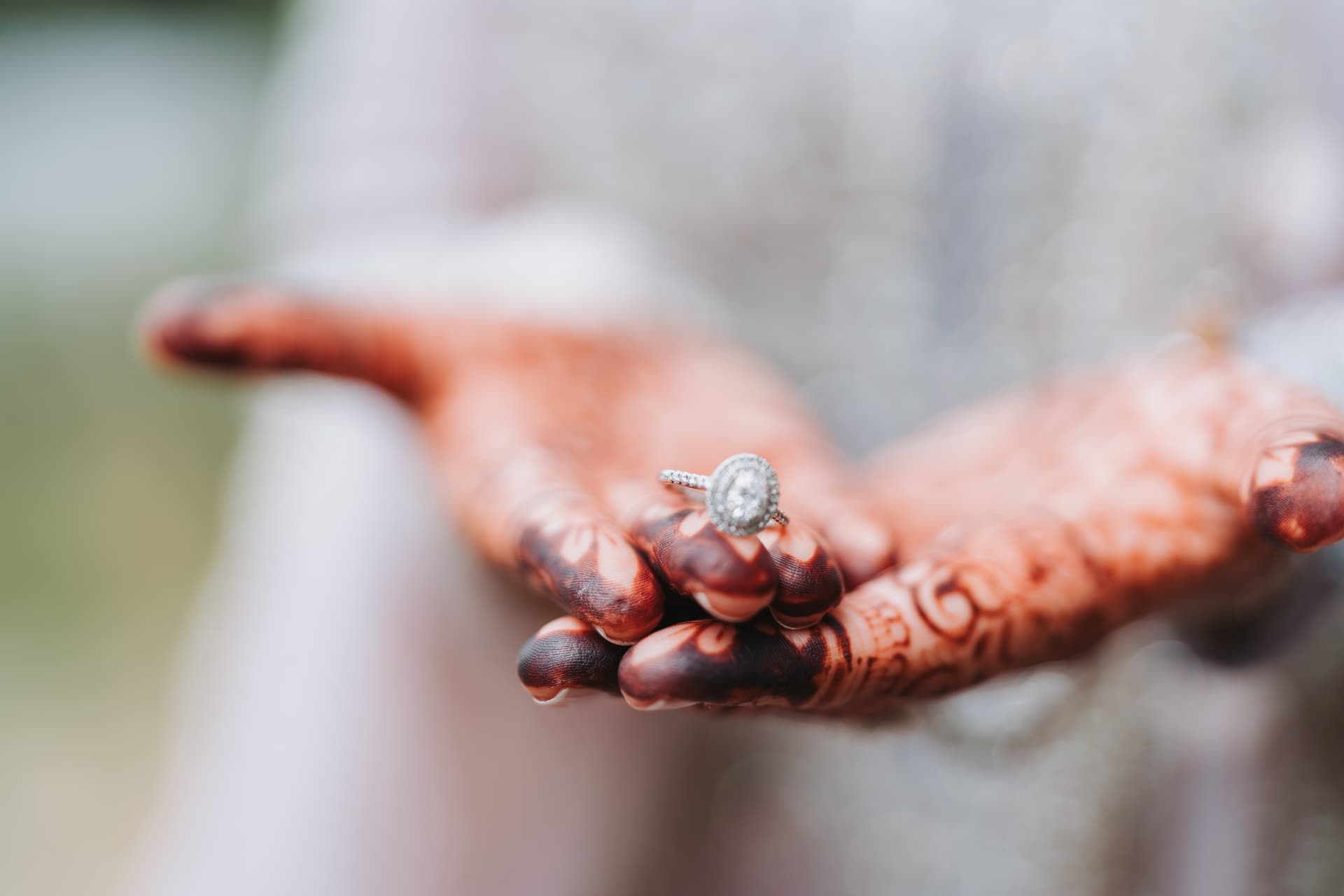 Bride's henna-adorned hand holding her engagement ring