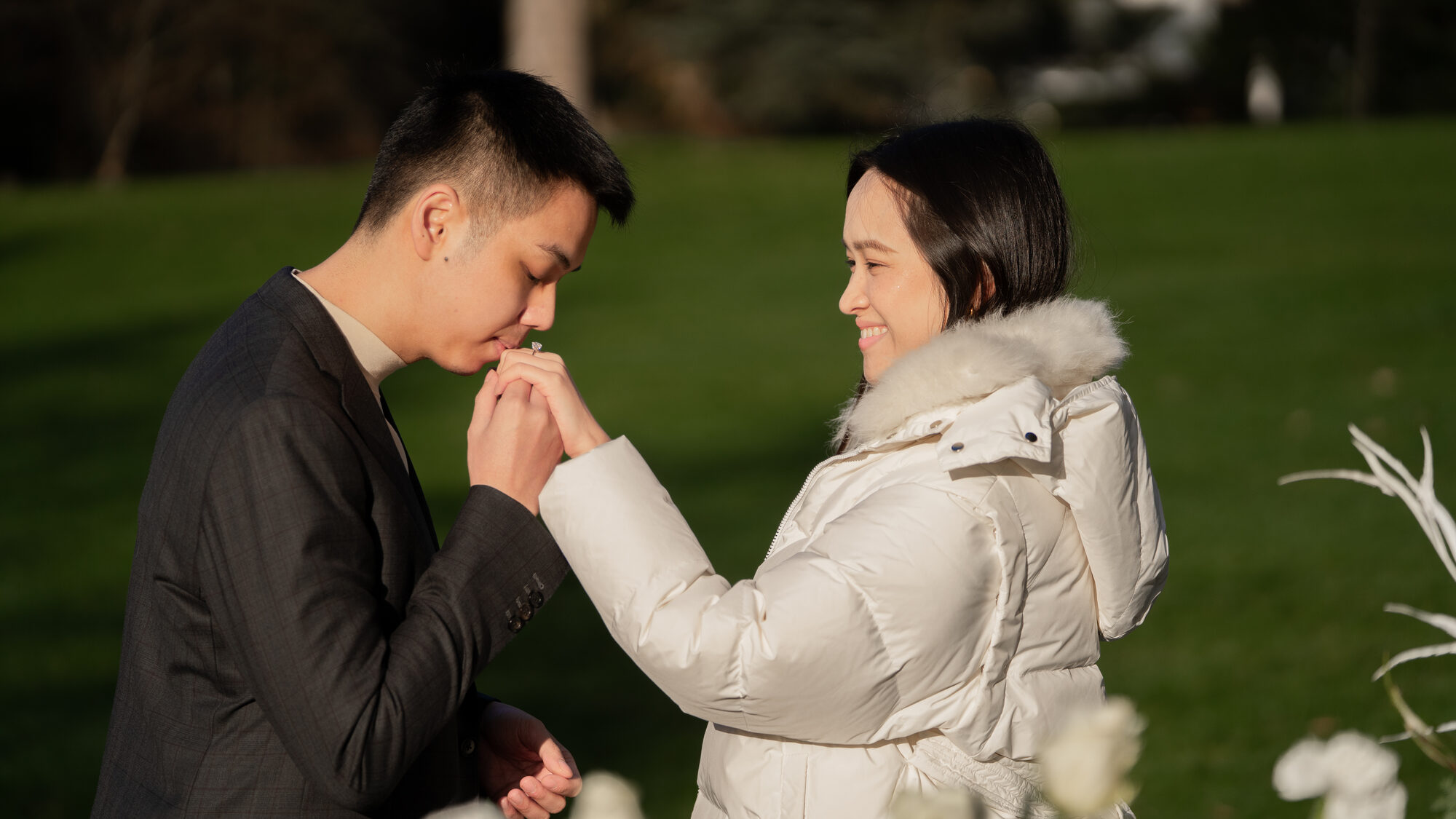Couple walking down a sunlit park path with a winter bouquet