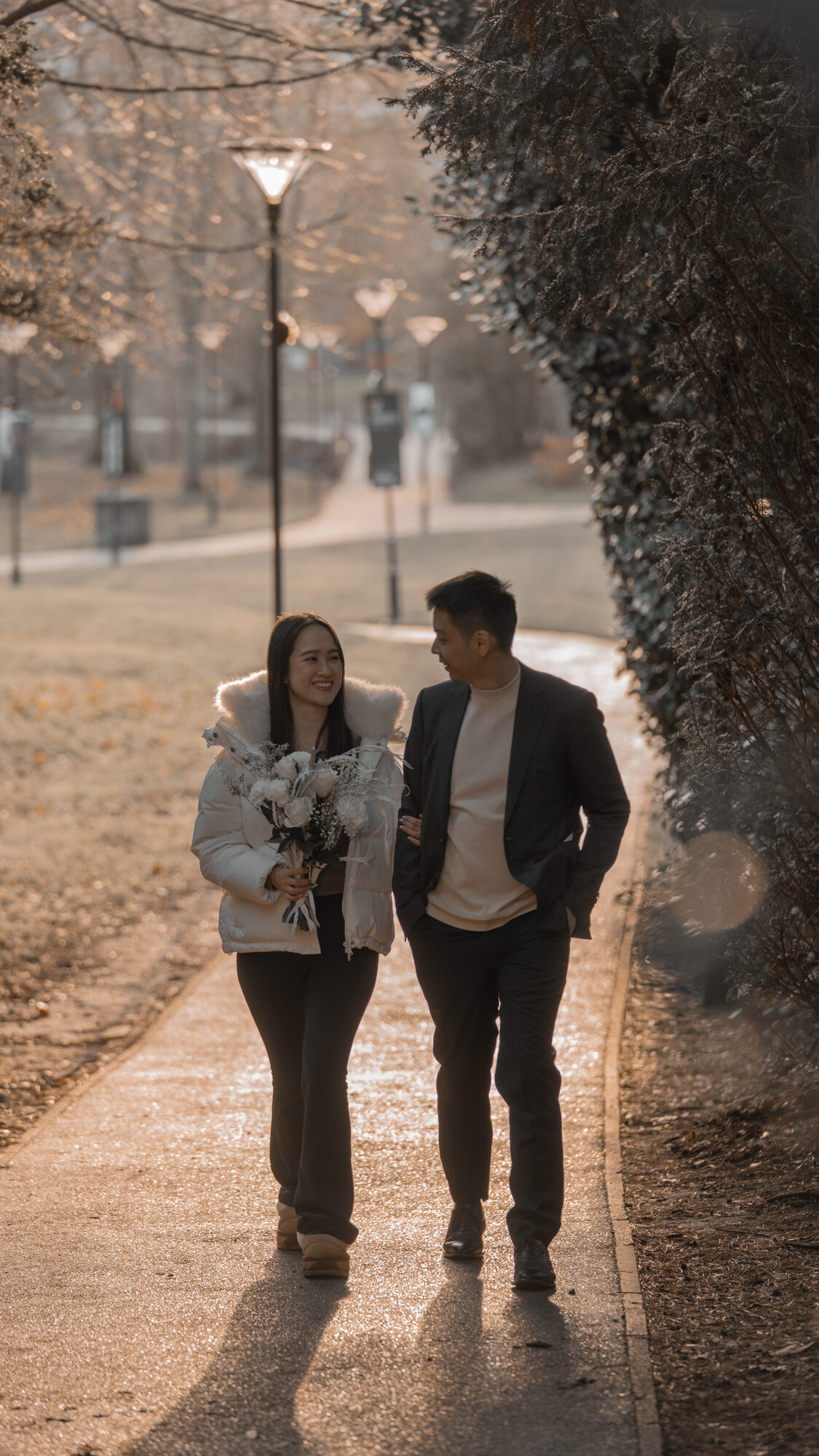 Groom kissing fiancée's hand on a bench at the University of Birmingham