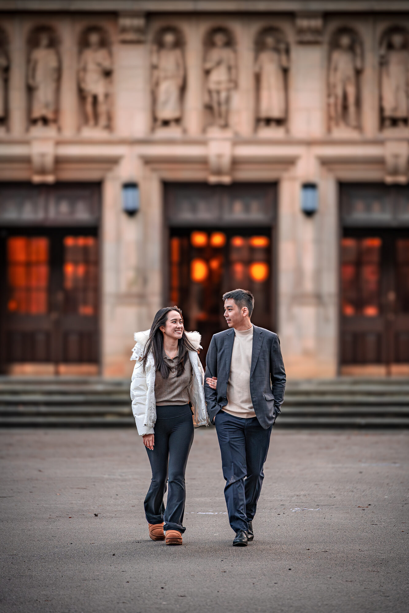 Engaged couple walking arm in arm through a winter park at sunrise