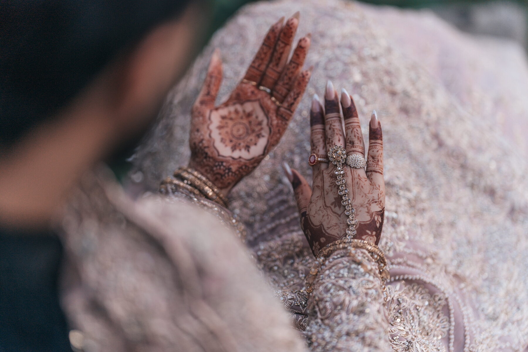 bride mehndi hands resting on bridal lehenga