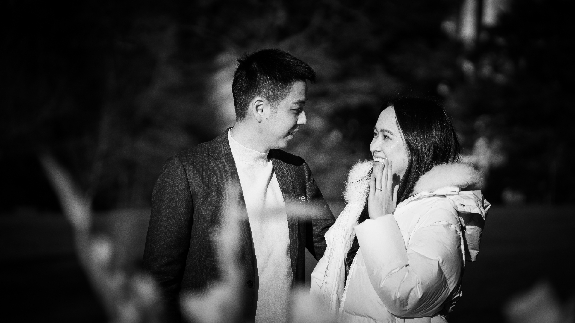 Black and white portrait of newly engaged couple laughing
