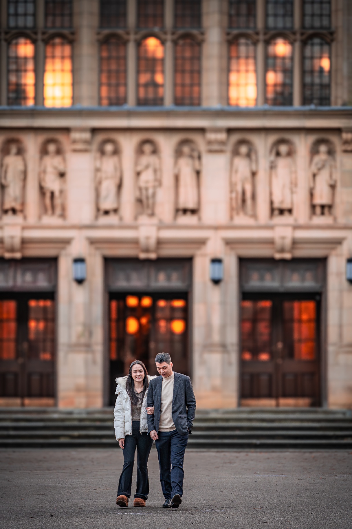 Couple walking in front of the Aston Webb Great Hall facade at dusk